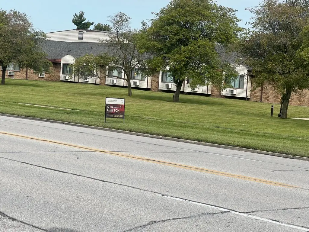Stretch Property Maintenance yard sign on a freshly mowed commercial property off Meredith Drive, from a lawn care company in Urbandale, IA