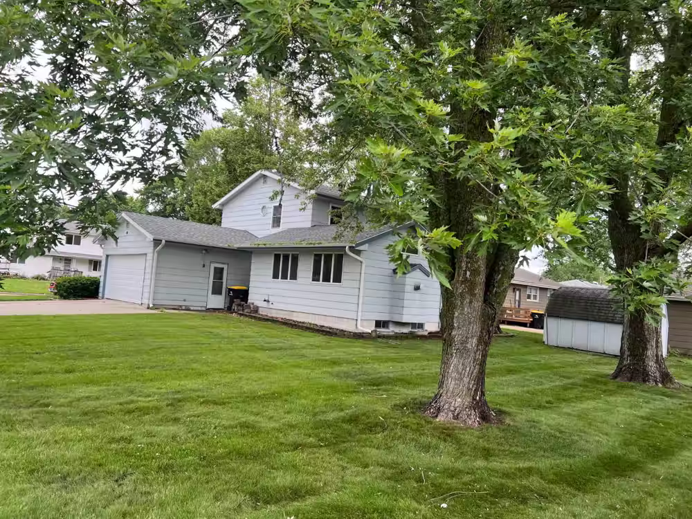 Freshly mowed, striped lawn with mature shade trees at a home in Waukee, IA, maintained by Stretch Property Maintenance