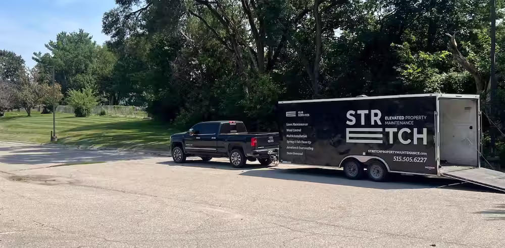 Stretch Property Maintenance truck and trailer at a freshly mowed commercial property in West Des Moines, IA