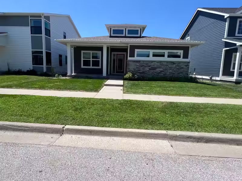 After: the same West Des Moines, IA front lawn freshly mowed and edged by Stretch Property Maintenance